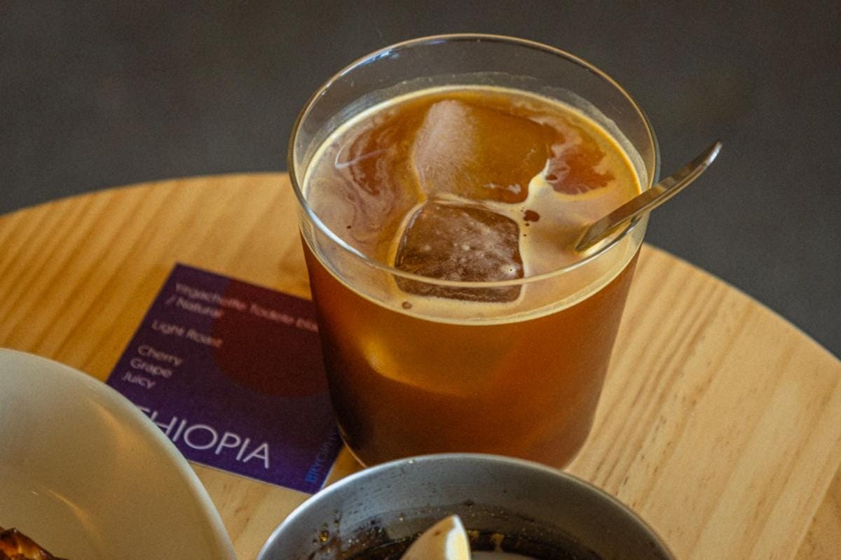 ImagePrompt: A variety of coffee beans displayed with labels indicating origins like Ethiopia, Colombia, and Brazil, set alongside different brewing equipment.