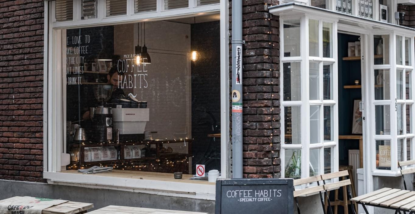 A cozy Dutch café with aromatic coffee cups on rustic tables and friendly baristas serving Dutch specialty brews.